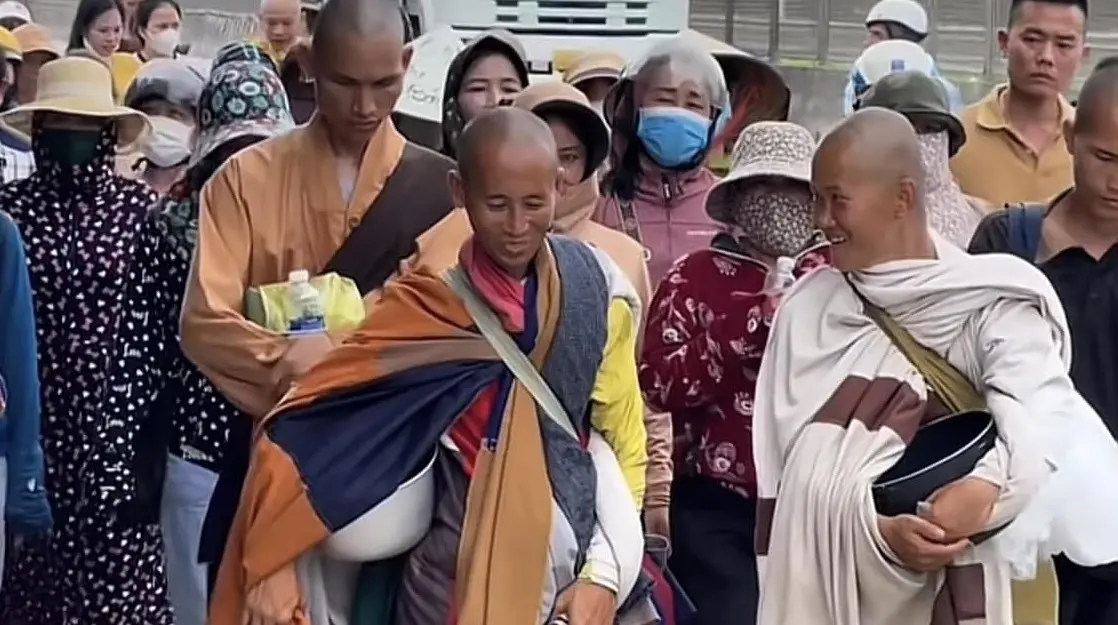 Hình ảnh ông Thích Minh Tuệ đi bộ trên đường với nhiều người vây quanh